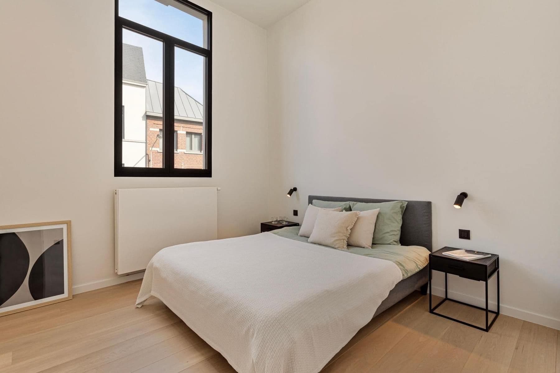 Rustige wit-getinte slaapkamer met een strak zwart Ferro 99 draaikiepraam