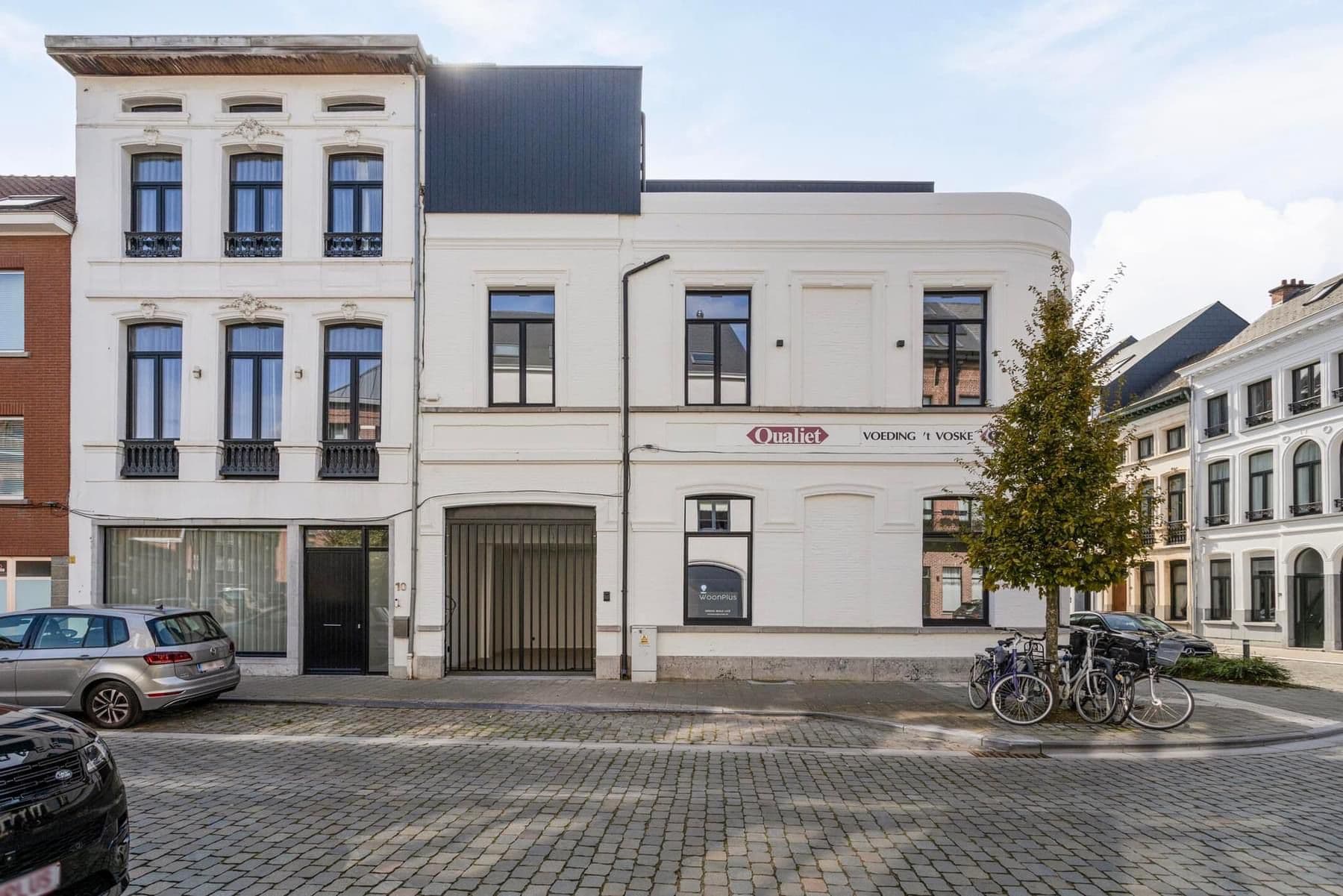 Detail van de strakke witte voorgevel met donker inliggend aluminium schrijnwerk in Lier