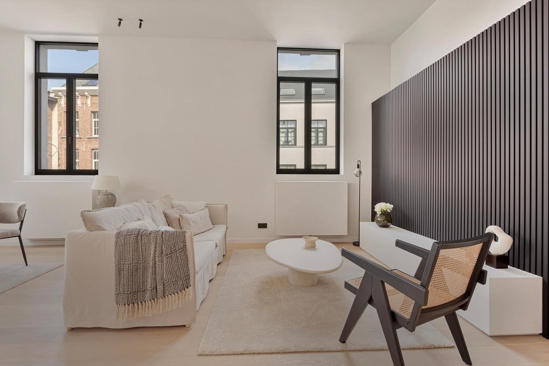 Moderne woonkamer in Lier voorzien van donkere, minimalistische aluminium ramen voor een warm contrast