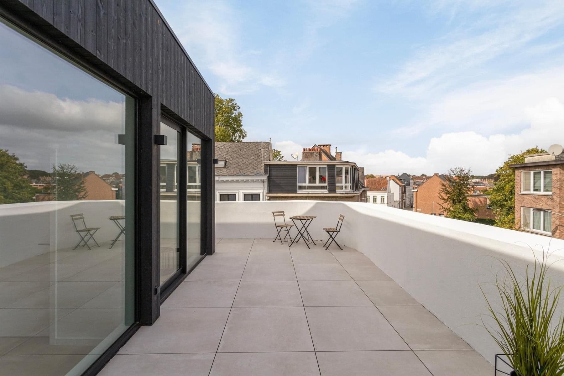 Groot SS55 aluminium schuifraam met slanke profielering op de bovenverdieping, aansluitend op een dakterras