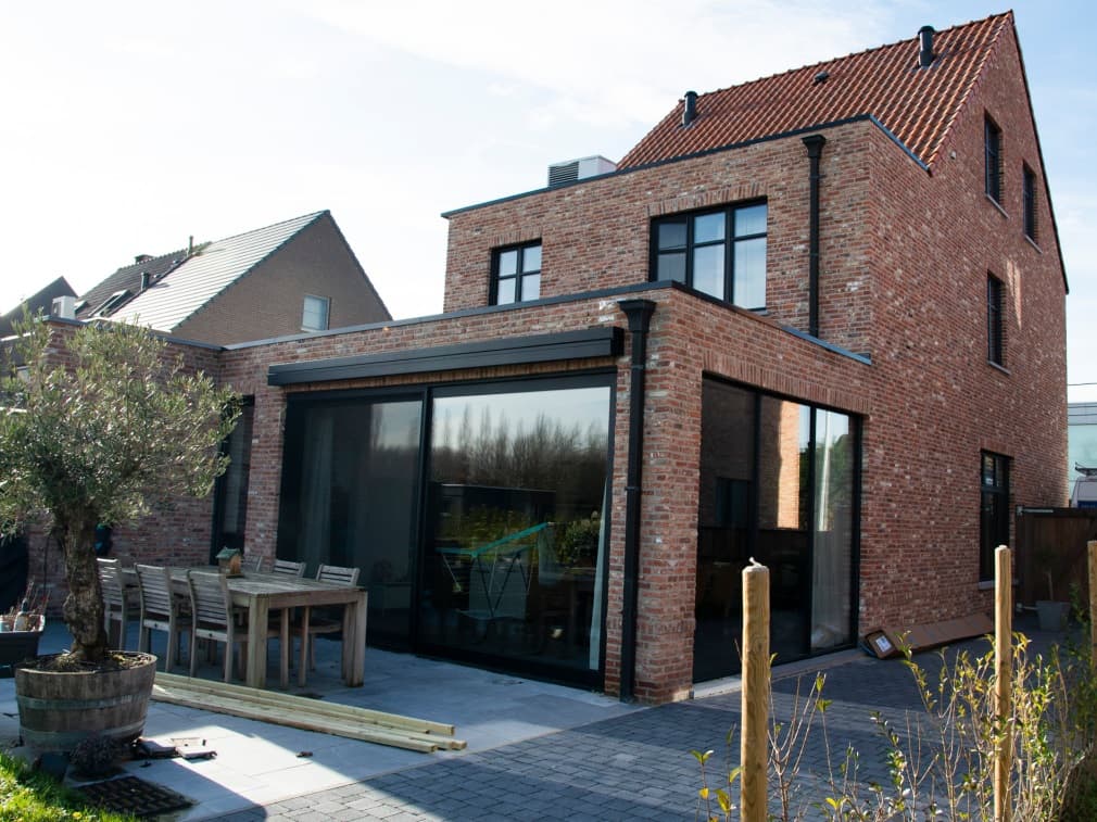 Achtergevel in Lier met Ferro99 ramen, SS70 schuifraam en knikarm zonwering