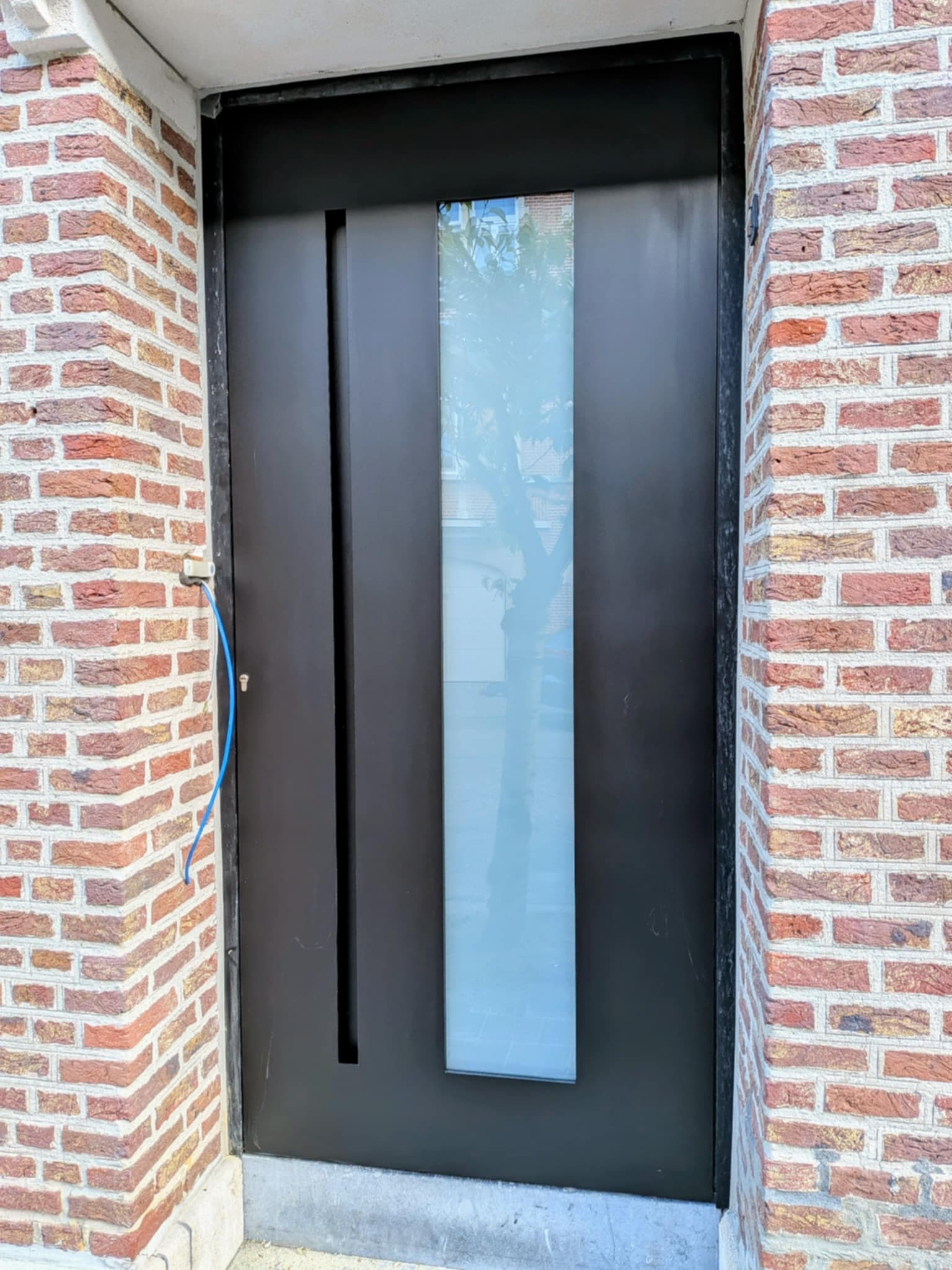 Zwarte voordeur met Magnitude paneel van Frager, ingefreesde deurtrekker en gezandstraald glas